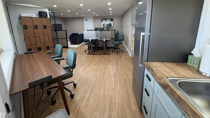 The kitchen end of Harbor: lockers, a full-height refrigerator, sink and counter, beside a standing-height work table.